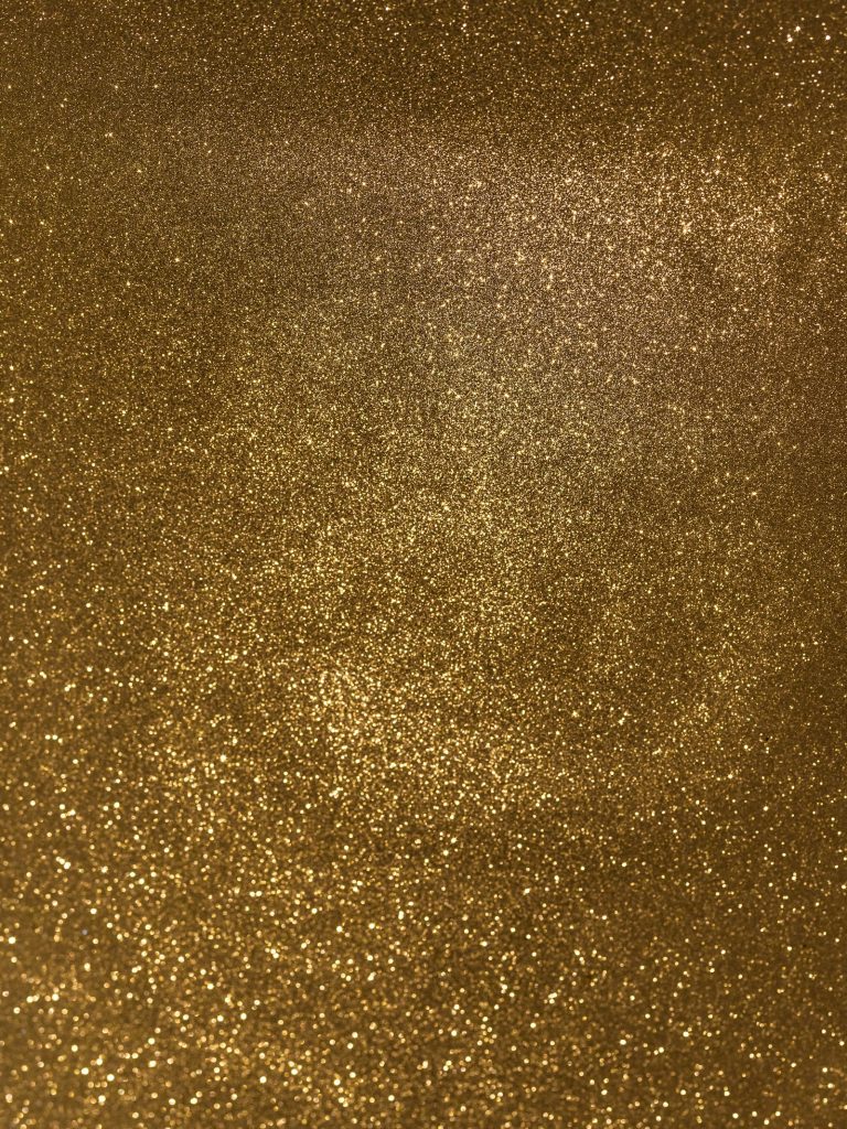 Fine gold glitter particles under warm light