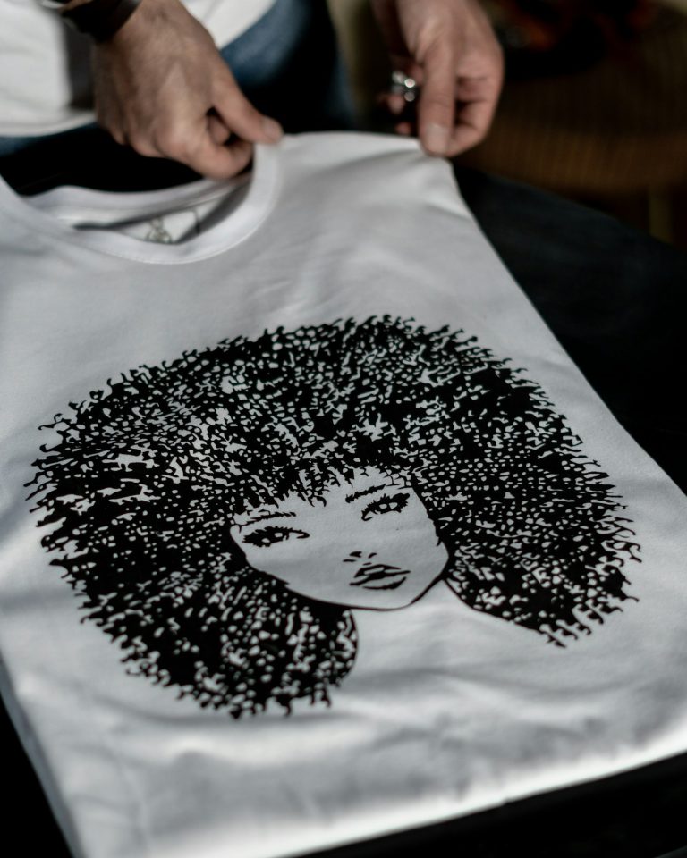 Hands holding a white t-shirt with a black illustration