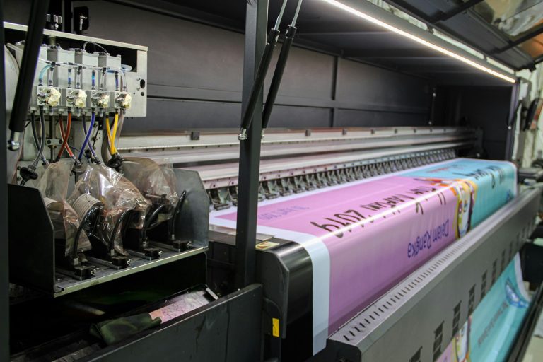 Wide-format printer printing a pink banner