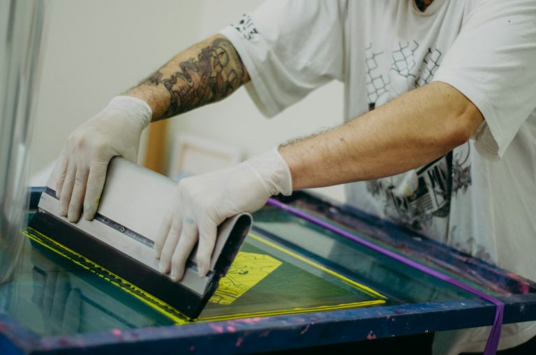Gloved hands pulling a squeegee across a screen
