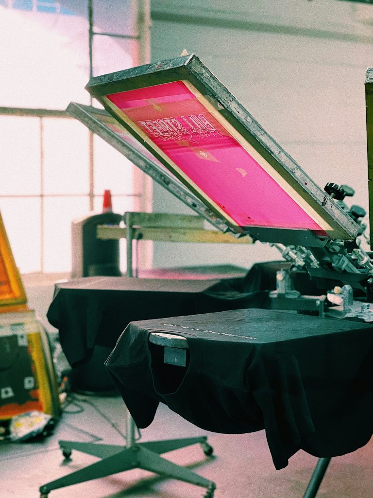 Manual screen printing press with a pink screen
