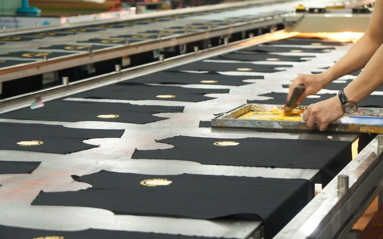 Long printing table with garment panels laid out for printing