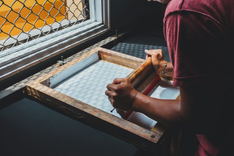 Hands pulling a squeegee through a wooden screen frame